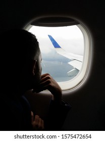 A Man Looking Out Of A Plane Window 