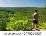 A man looking out of the shepaug river valley from the top of Steep Rock in Washington Depot Connecticut. 