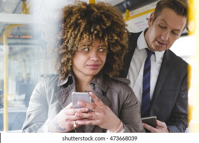 Man Looking Over A Womans Shoulder On The Train At Her Phone Screen. 