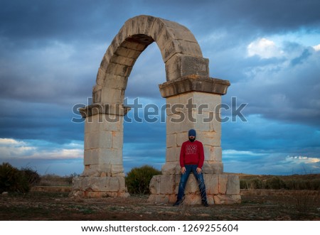 Man looking at a Roman arch on the Via Augusta of Spain