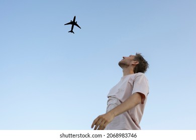 man looking up in the sky and cheer the airplane 