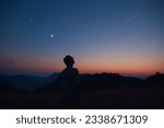 Man looking at the starry skies, crescent Moon and shooting star in blue hour twilight time.