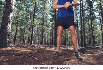 Man looking at stopwatch to check gps pace and time on trail run - Powered by Shutterstock