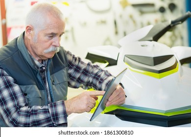 Man Looking At Tablet Next To Jet Ski In Store