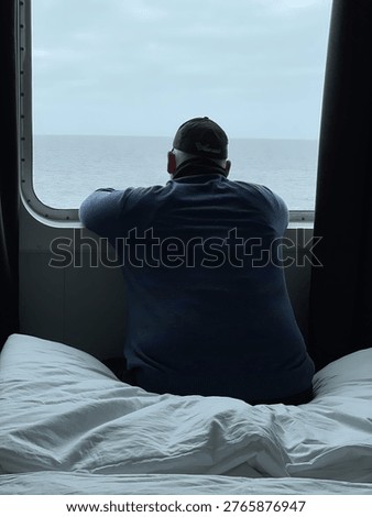 Man looking through cabin window at sea during cruise