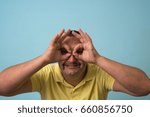 man looking through hands, making binoculars