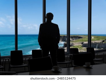 Man looking through office window dreaming about ocean beach. Vacation concept