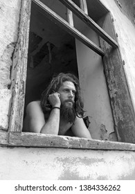 Man Looking Through The Old Window In Black And White.