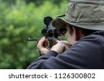 A Man Looking through a scope on a hunting rifle close up
