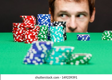 man looking under the table on a bunch of playing chips