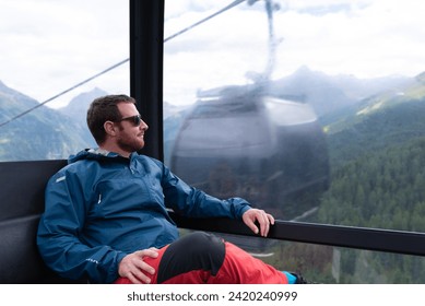 Man looking at views inside of a cable car in a ski resort during summer season.
