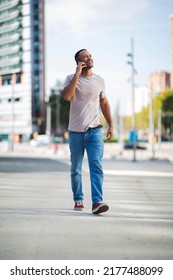 Man looking up while talking on mobile phone and walking outdoors in city