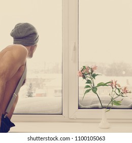 Man looking in window on cold winter day at home, image with warm vintage toning