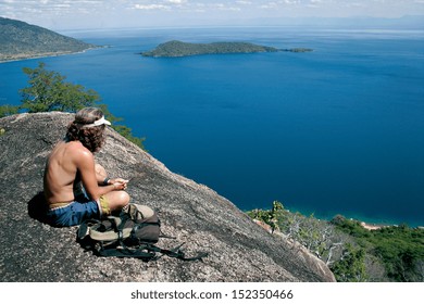 A Man Looks Out Over Lake Malawi From The Top Of A Mountain.