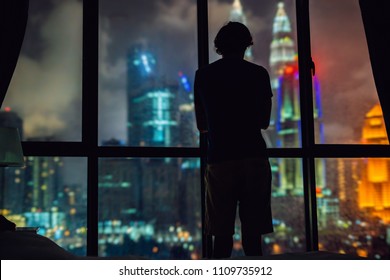 Man Looks Out The Window At The Night City.