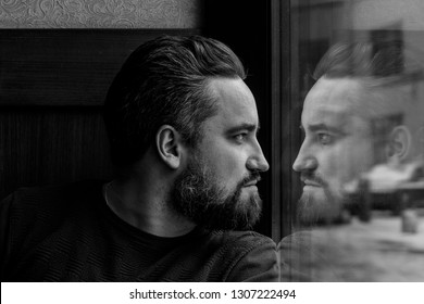 A Man Looks Out The Window And Sees His Reflection