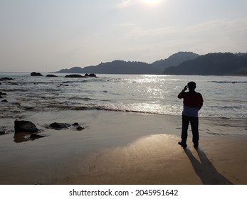 A Man Looks At The Sunset On A Shark Tooth Beach