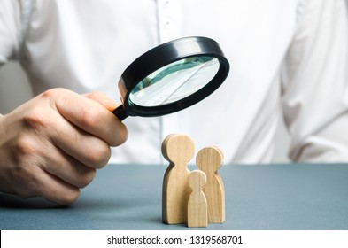 A man looks through a magnifying glass at a family figure. The study of family composition and demographic situation. Statistical data. The program of support for young families, financial assistance.