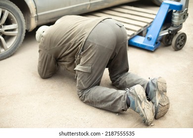 Man Looks Under Car. Wheel Replacement. Repair Of Transport. It's Tough Task. Guy On Pavement.