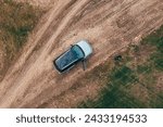 Man lost off-track on countryside road exiting out of the car and looking around, aerial shot from drone pov, top down
