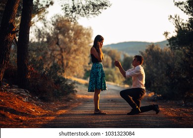 Man in love proposing a surprised,shocked woman to marry him.Proposal, engagement and wedding concept.Betrothal.Being affianced to love of life.Kneeling,getting down on knees.Ring offering.Marriage