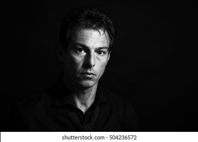 Man low key high-contrast portrait with a serious look on his face. - Powered by Shutterstock