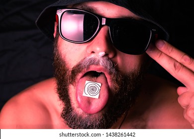 Man with LSD on the tongue. On a black background.