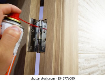 A man lubricates door hinges with oil.
