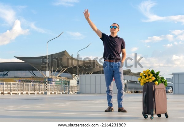 A man with luggage meets passengers at the\
airport car park. Business trip,\
vacation