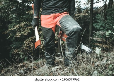 Man lumberjack with axe and chainsaw going to hard work in the wood Concept of hard work and sustainable economy