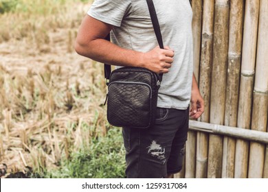 Man with luxury snakeskin python leather handbag. Bali island background.