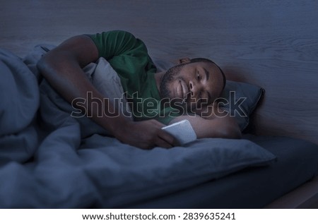 Man Lying In Bed Using Smartphone At Night, Focused On Screen, Sleep Concept