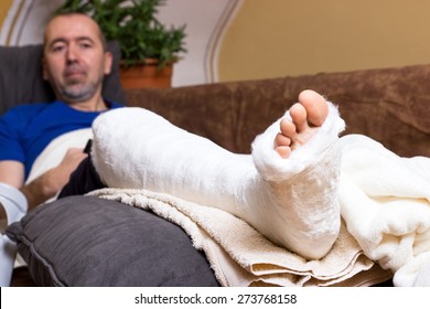A man lying with a broken foot on the sofa at home