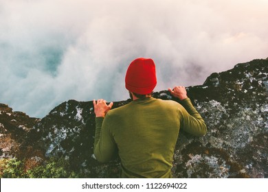 Man lying down on the edge cliff above clouds gaze into abyss mountains travel adventure lifestyle extreme vacations  - Powered by Shutterstock