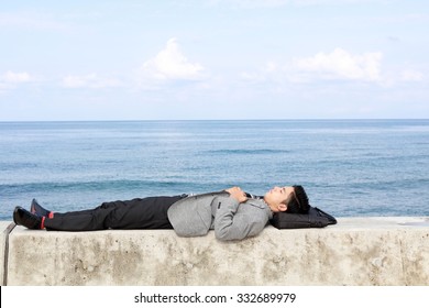 Man lying down on seawall