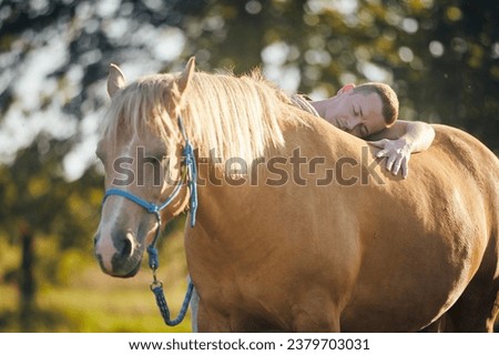 Man lying embracing of therapy horse. Themes hippotherapy, care and friendship between people and animals.
