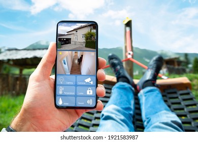 Man Lying In Hammock Watching CCTV Footage From House Security System