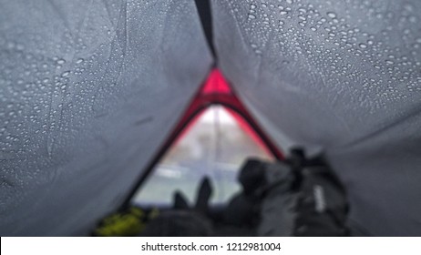 Man Lying Inside A Tent On A Rainy Day With Water Drops On The Walls