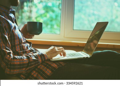 man lying with laptop drinking coffee or tea