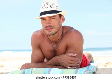 Man Lying On The Beach In A  Straw Hat