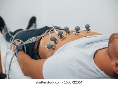 Man lying on the bed in the clinic and getting electrocardiogram test.
