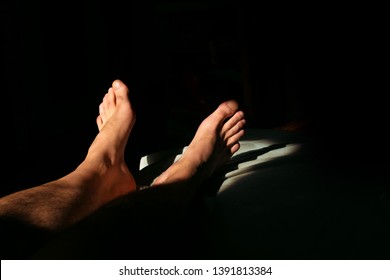 The man is lying on the bed and is resting.naked male legs in sunlight