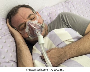 Man Lying On Bed With Sleeping Apnea And CPAP Machine