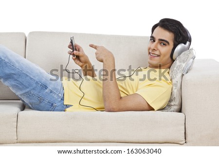 Man lying on a couch and listening to music on a mobile phone