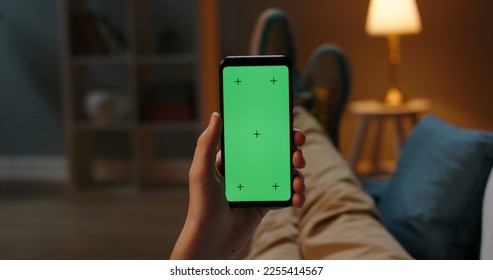 Man lying on couch using smartphone with chroma key green screen at night, scrolling through social media or online shop - internet, communications concept close up  - Powered by Shutterstock