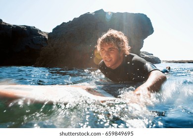 Man Lying On Surfboard In The Water