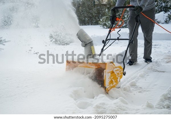 Man with machine\
removing snow in yard