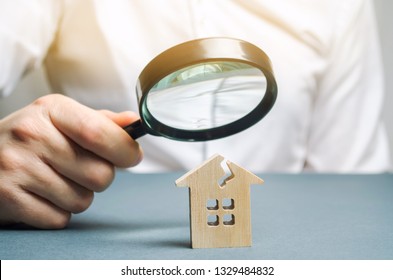 A Man With A Magnifying Glass Looks At A House With A Crack. Damage Assessment Home And Insurance Risks. Estimation Of The Cost Of Repair And Renovation Of Old Buildings, Property Value.