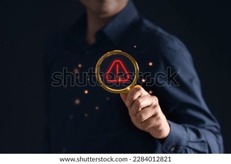 Man with magnifying glass and warning icon, symbolizing caution and scrutiny. Perfect for graphics, illustrations, and web design projects. Stock photo.