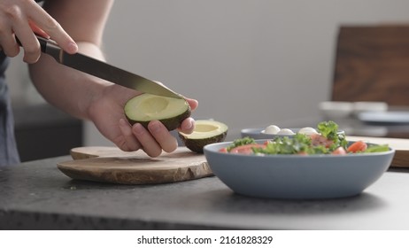 man make salad with kale, mozzarella, avocado and cherry tomatoes, cut avocado - Powered by Shutterstock